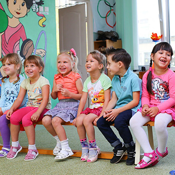 young children sitting in a classroom smiling and laughing