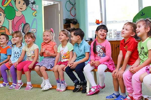young kids sitting in a classroom smiling and laughing