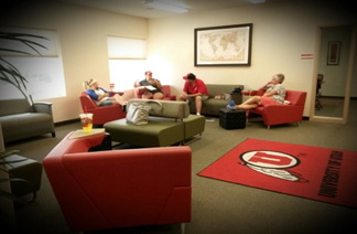 four people sitting in a large room with university of utah memorabilia having a discussion